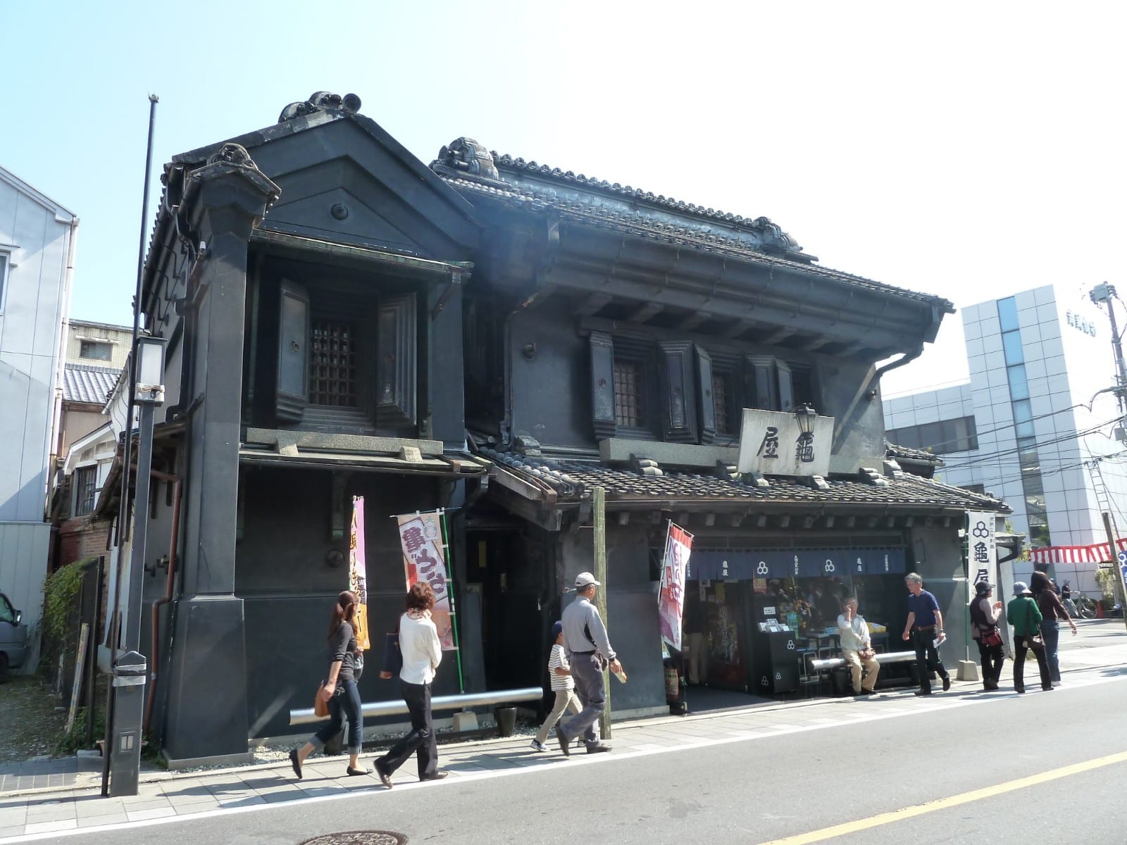 Kawagoe's street of black clay-walled kurazukuri merchant warehouses with people strolling.