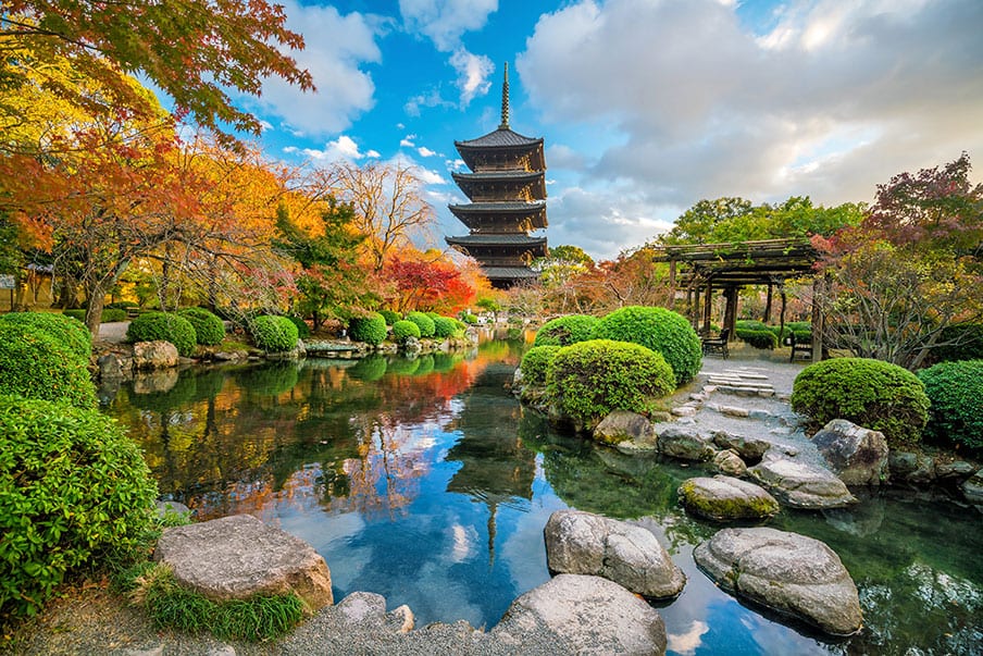 The five-storey pagoda of To-ji temple above an autumn garden and pond in Kyoto.