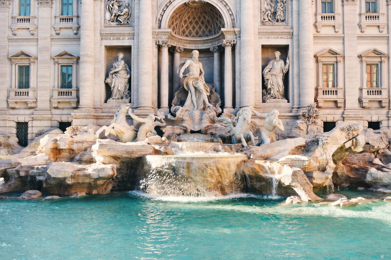 The Trevi Fountain's tritons and sea horses spill into its turquoise basin below the palace facade.