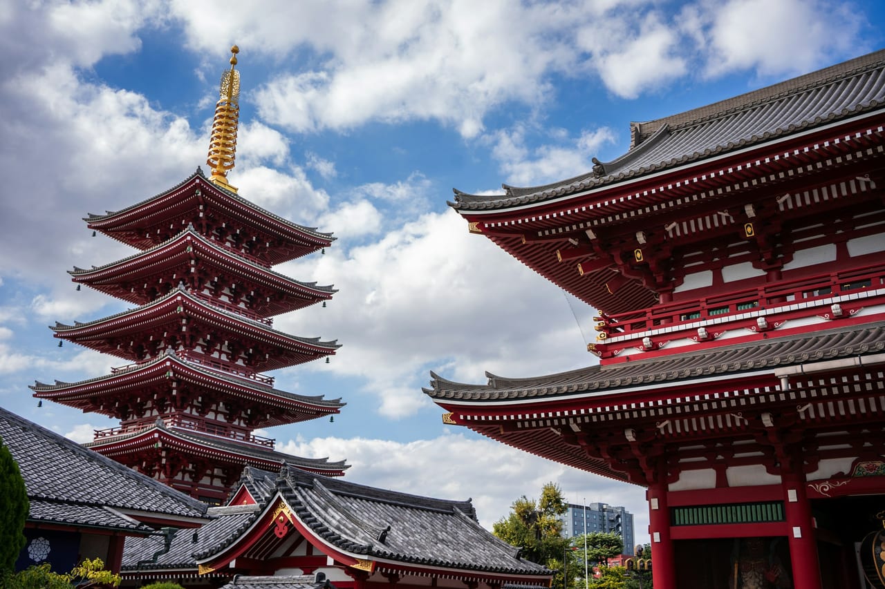 Senso-ji's vermilion five-story pagoda and the Hozomon gate rise against a bright blue sky in Asakusa.