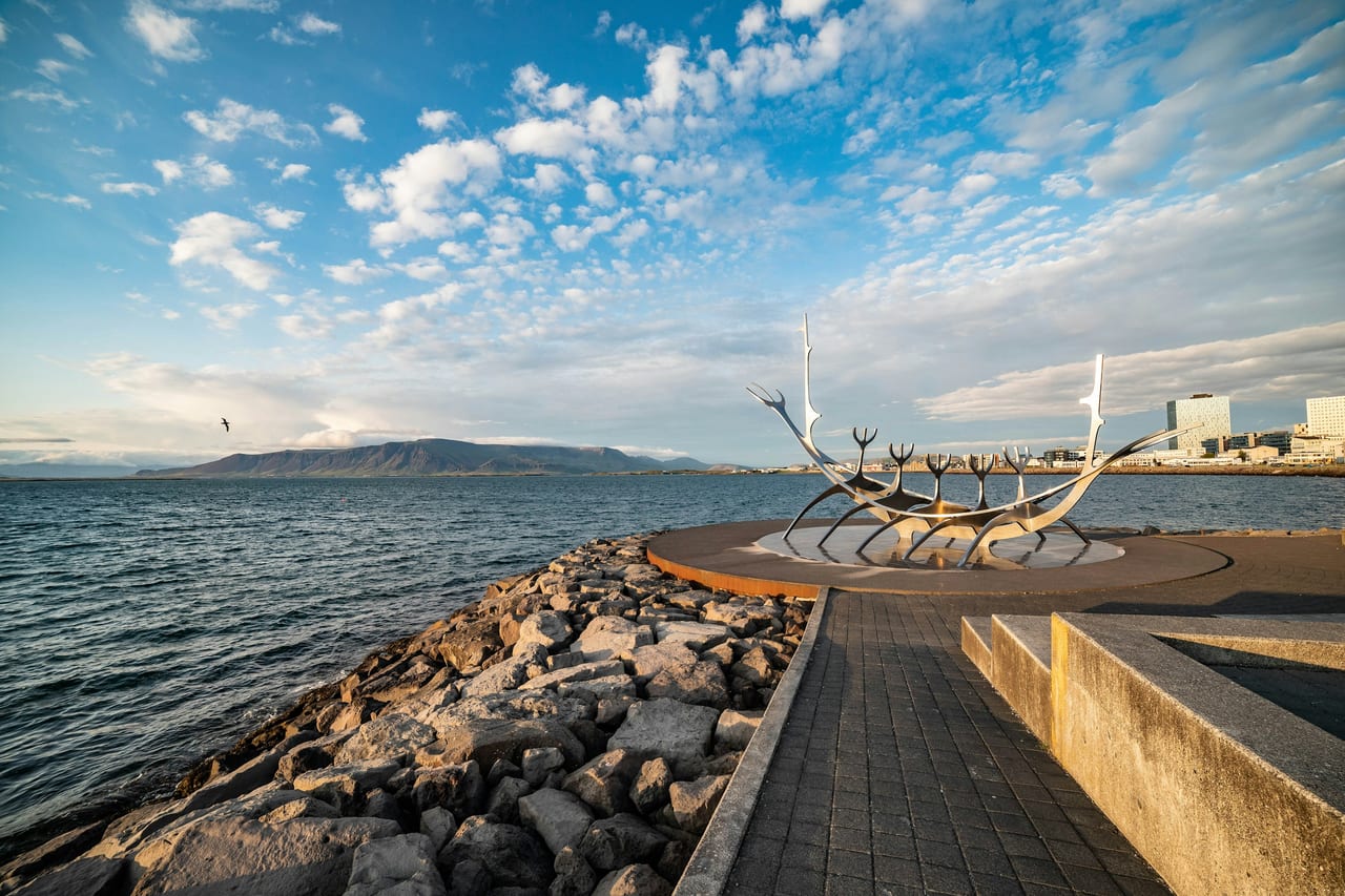The Sun Voyager sculpture stands beside the sea in Reykjavik under a bright blue sky.