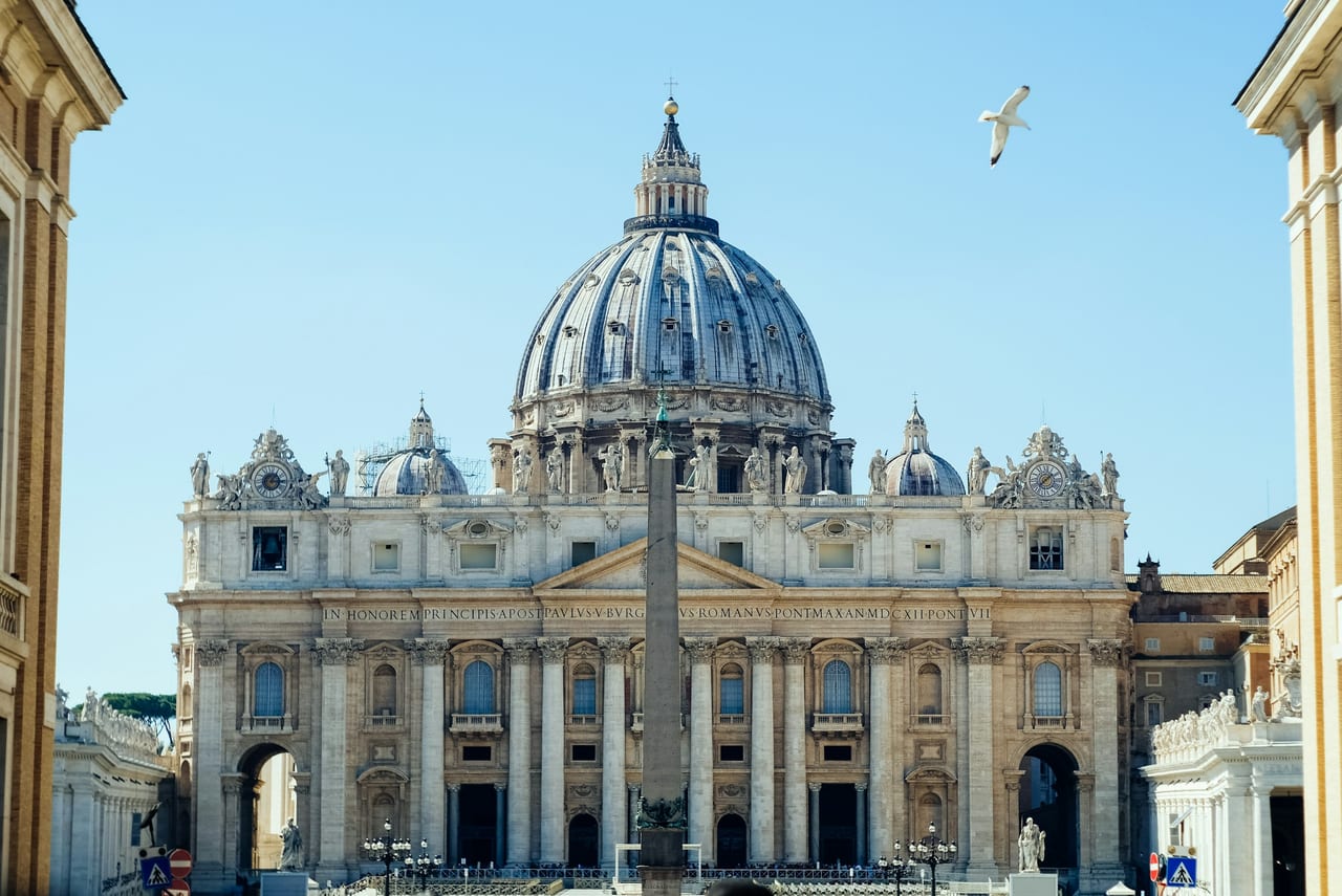 St Peter's Basilica and its great dome rise over the obelisk in St Peter's Square under a clear sky.