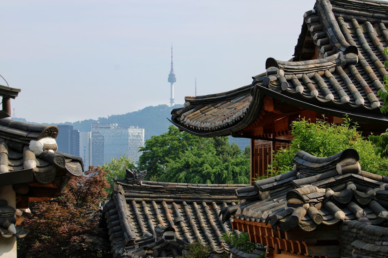 Traditional tiled rooftops frame N Seoul Tower and the Seoul skyline.