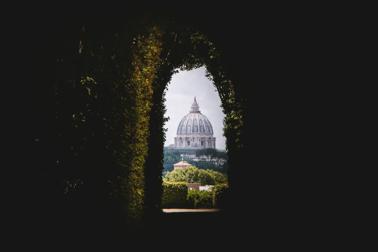 St Peter's dome sits framed at the end of a hedge-lined avenue, seen through the Aventine keyhole.