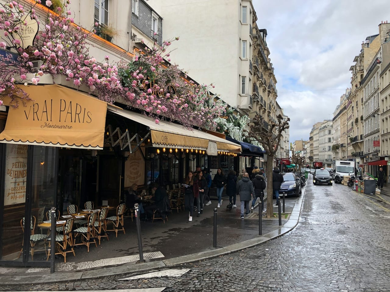 Café terrace in Saint-Germain, Paris, on a quiet morning with empty wicker chairs and a striped awning.
