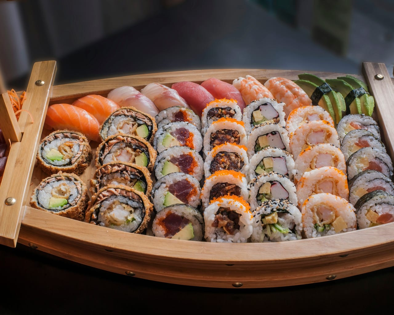 A wooden boat of assorted sushi rolls and nigiri at a Tokyo sushi counter.