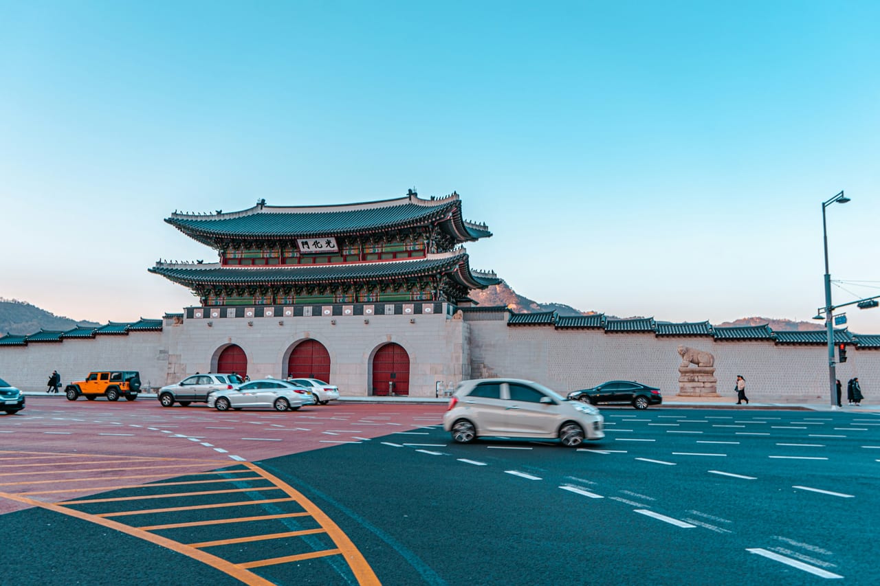 A gate of Gyeongbokgung Palace stands beside a broad roadway in Seoul.