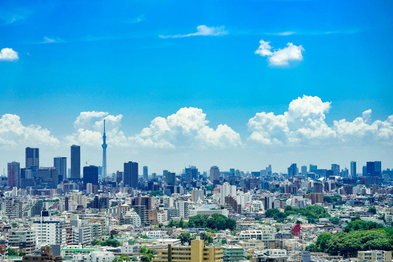 A clear-day view across central Tokyo's low-rise sprawl to the Skytree on the far horizon under a bright blue sky.