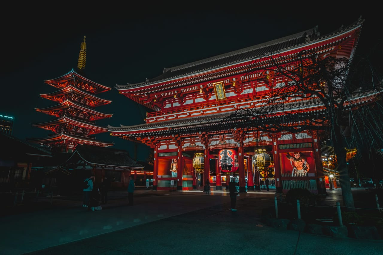 The red-lantern-lit Hozomon gate and five-story pagoda of Senso-ji glow against the night in Asakusa.