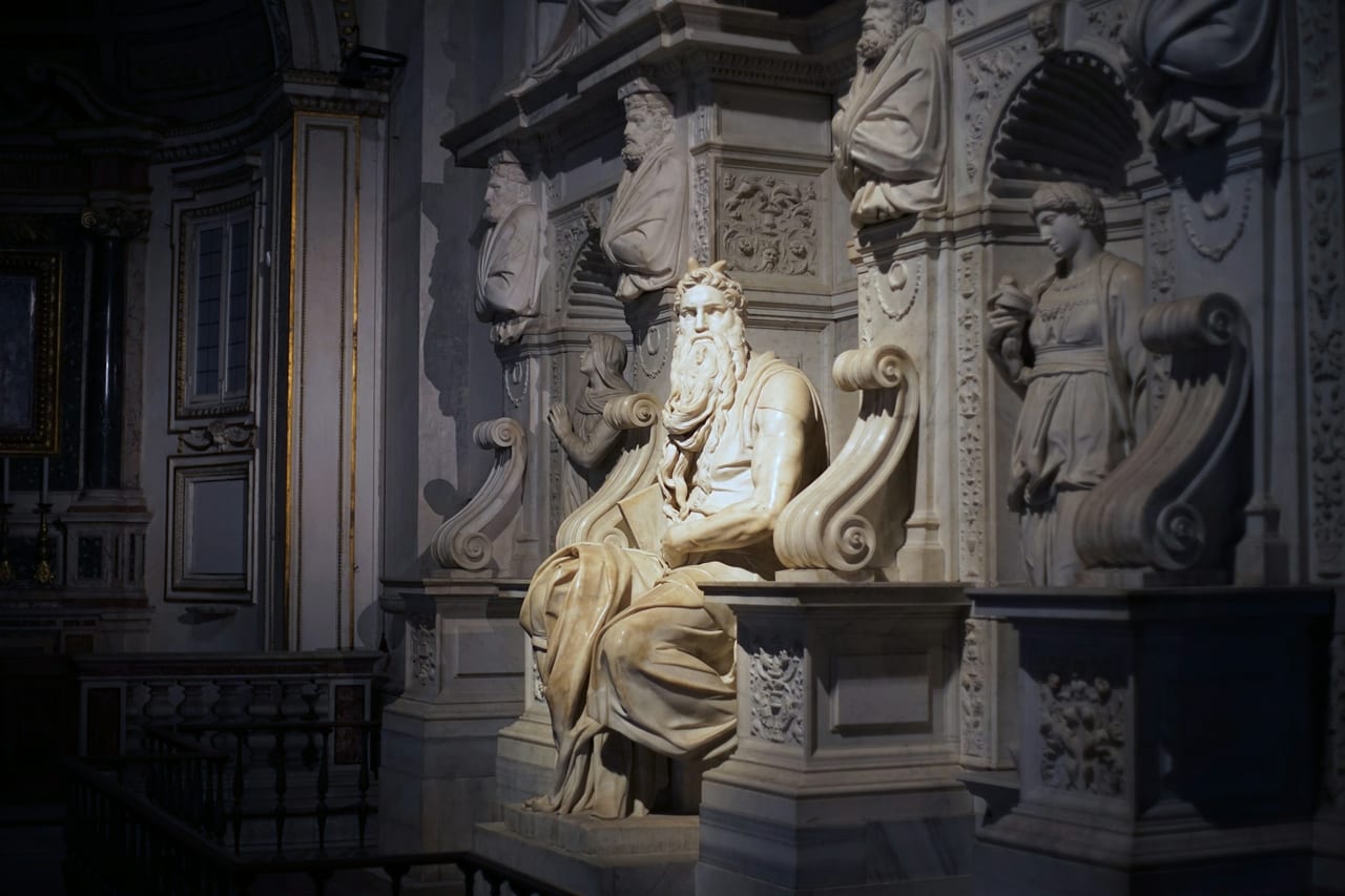 Michelangelo's horned, seated marble Moses holds the tablets in the dim tomb of Julius II.
