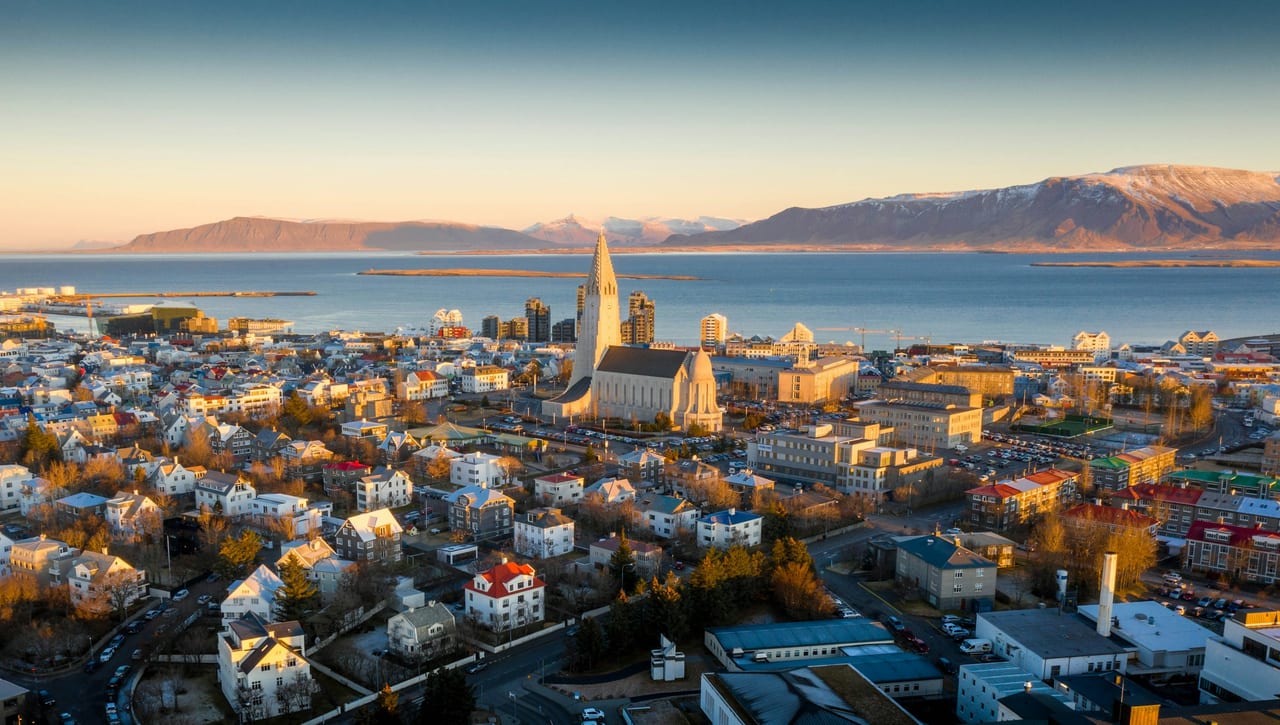 Aerial view of Reykjavik with Hallgrimskirkja church, the harbor, and mountains beyond.