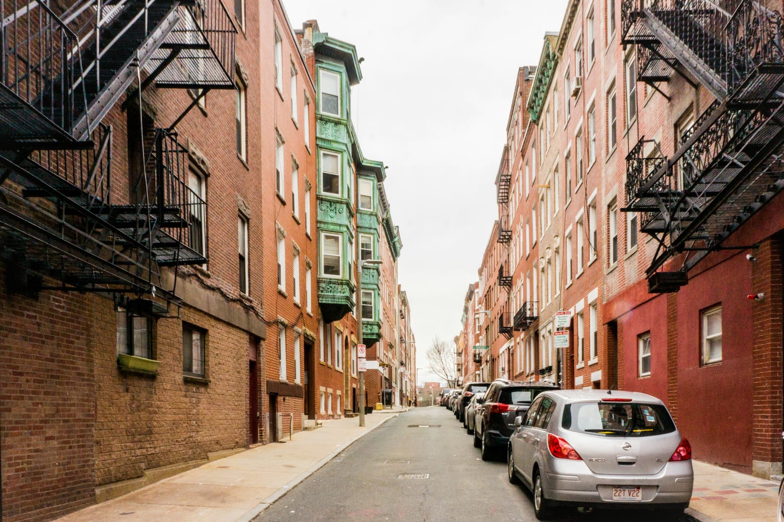 Narrow street in Boston's North End with brick buildings and restaurant awnings