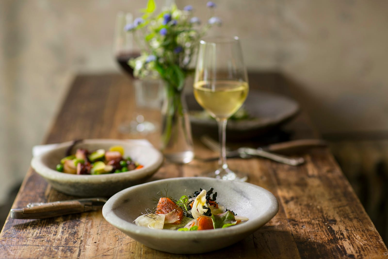 A spread of tapas-style small plates and wine glasses on a candlelit table.