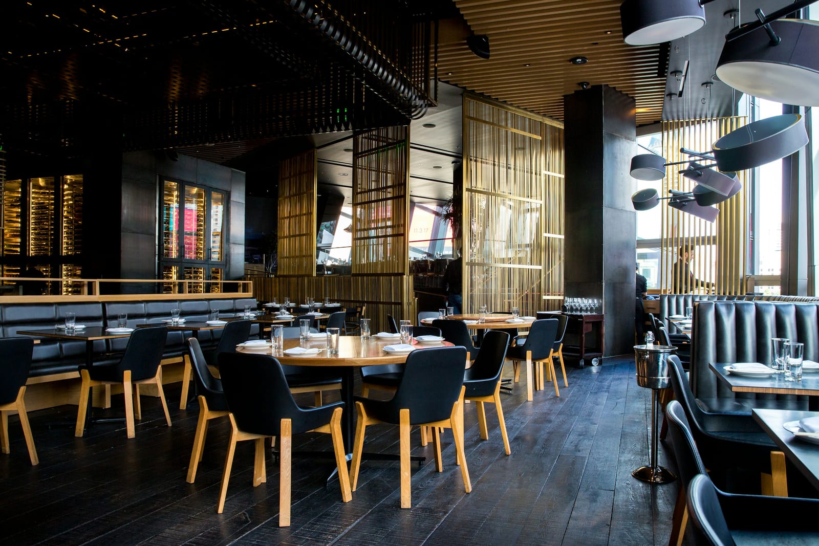 A cozy restaurant interior with brick walls, pendant lights and diners at candlelit tables.