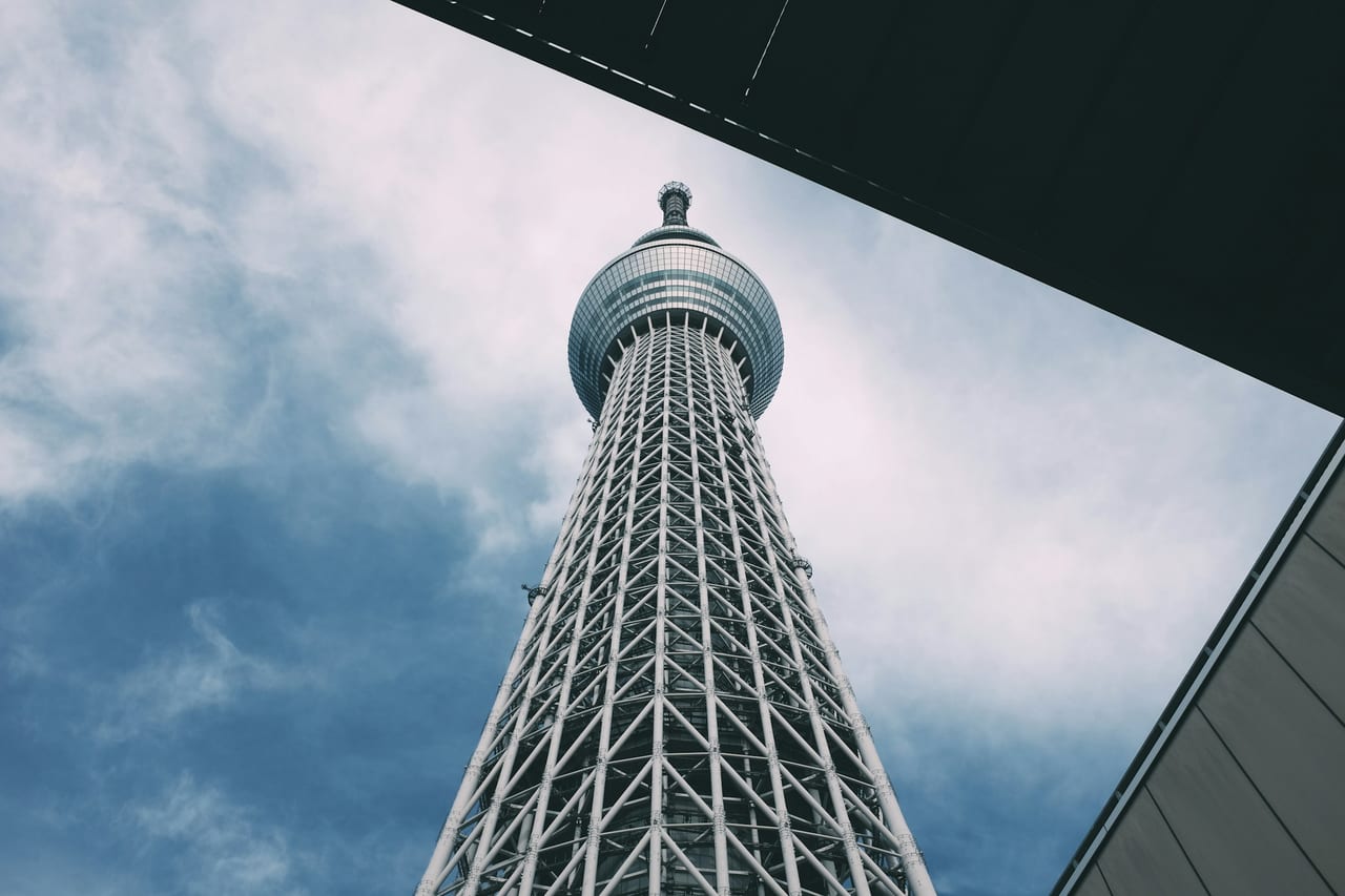 The Tokyo Skytree's pale spire rises far above the surrounding cityscape under a soft afternoon sky.