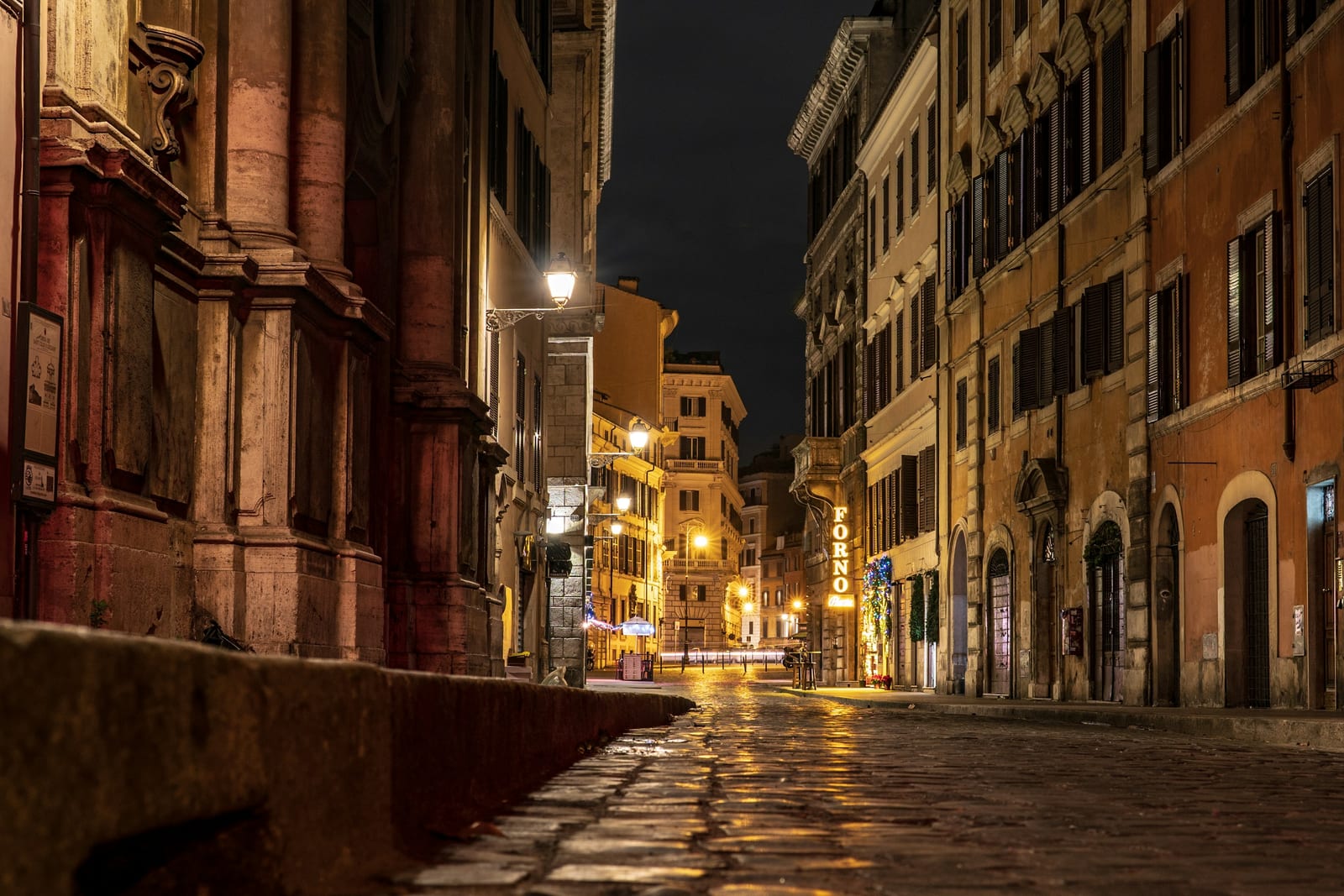 A lamplit cobblestone lane in Trastevere at night.