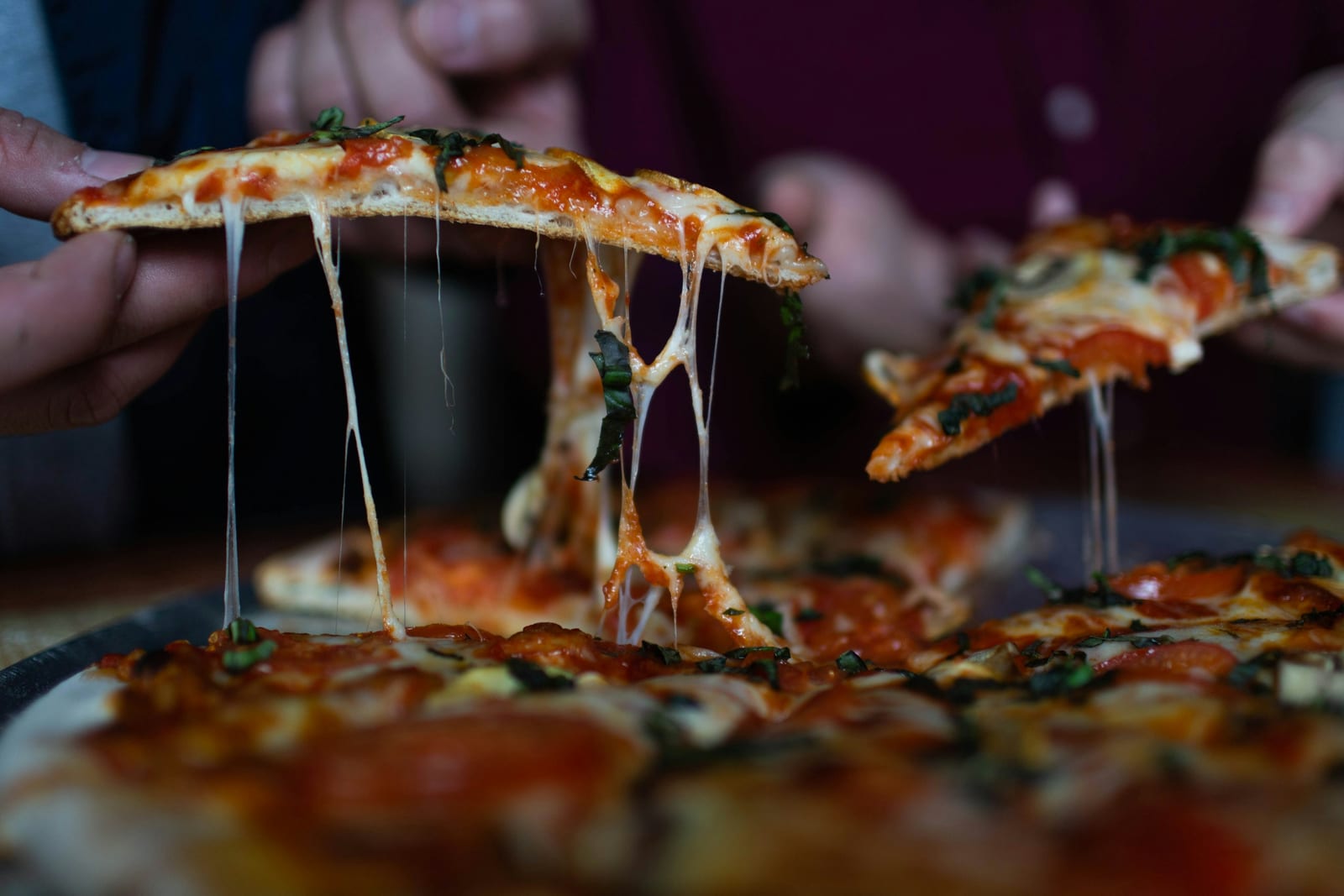 A slice of pizza al taglio topped with prosciutto and basil on a paper plate at Pizzarium.