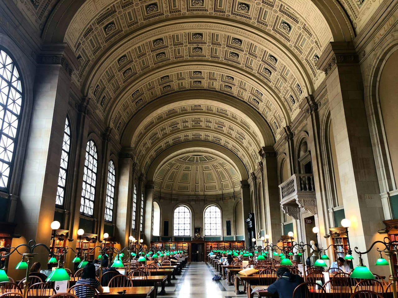 The barrel-vaulted ceiling and long rows of reading lamps in Bates Hall at the Boston Public Library.