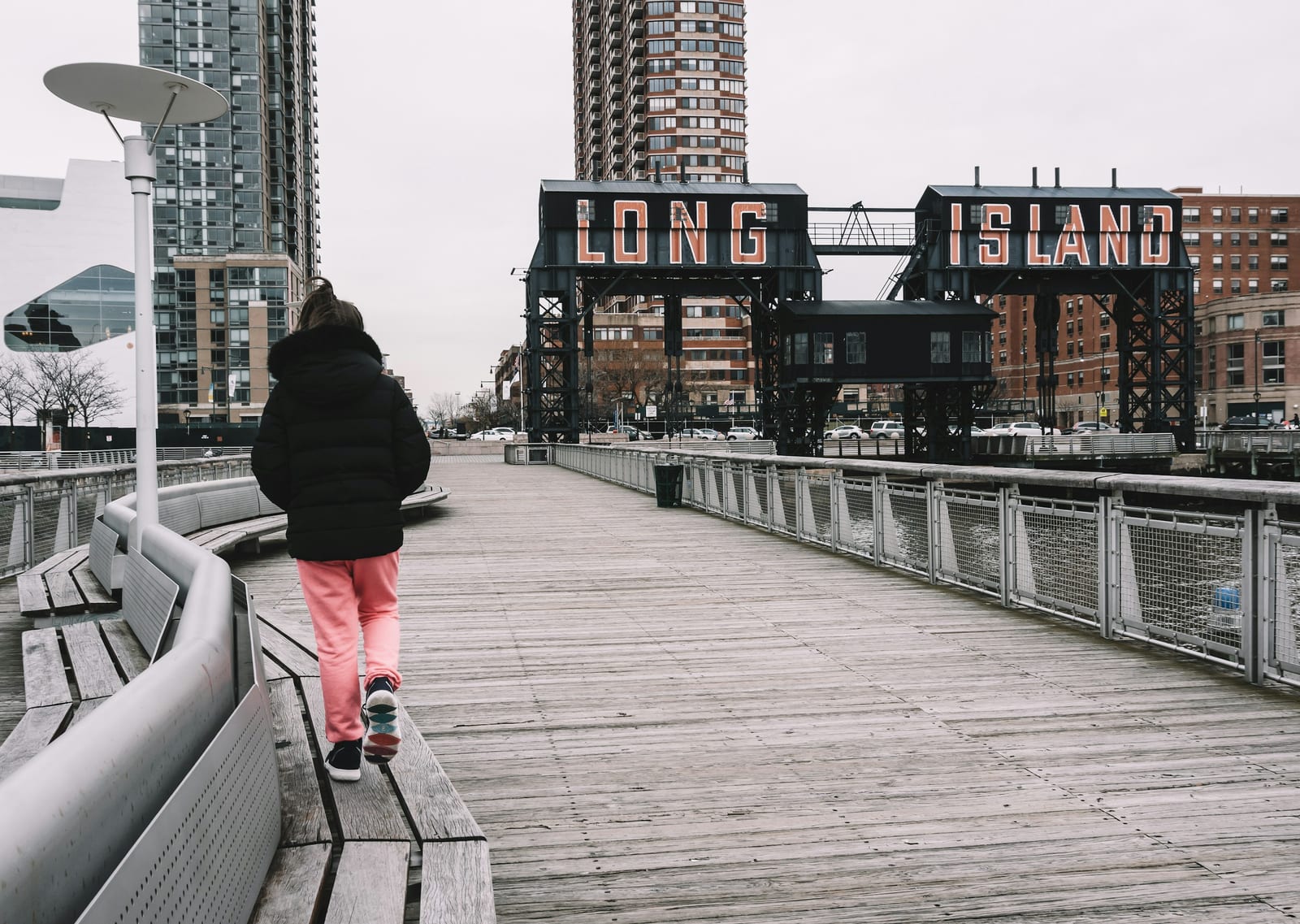 girl wearing black bubble hoodie walking near bench