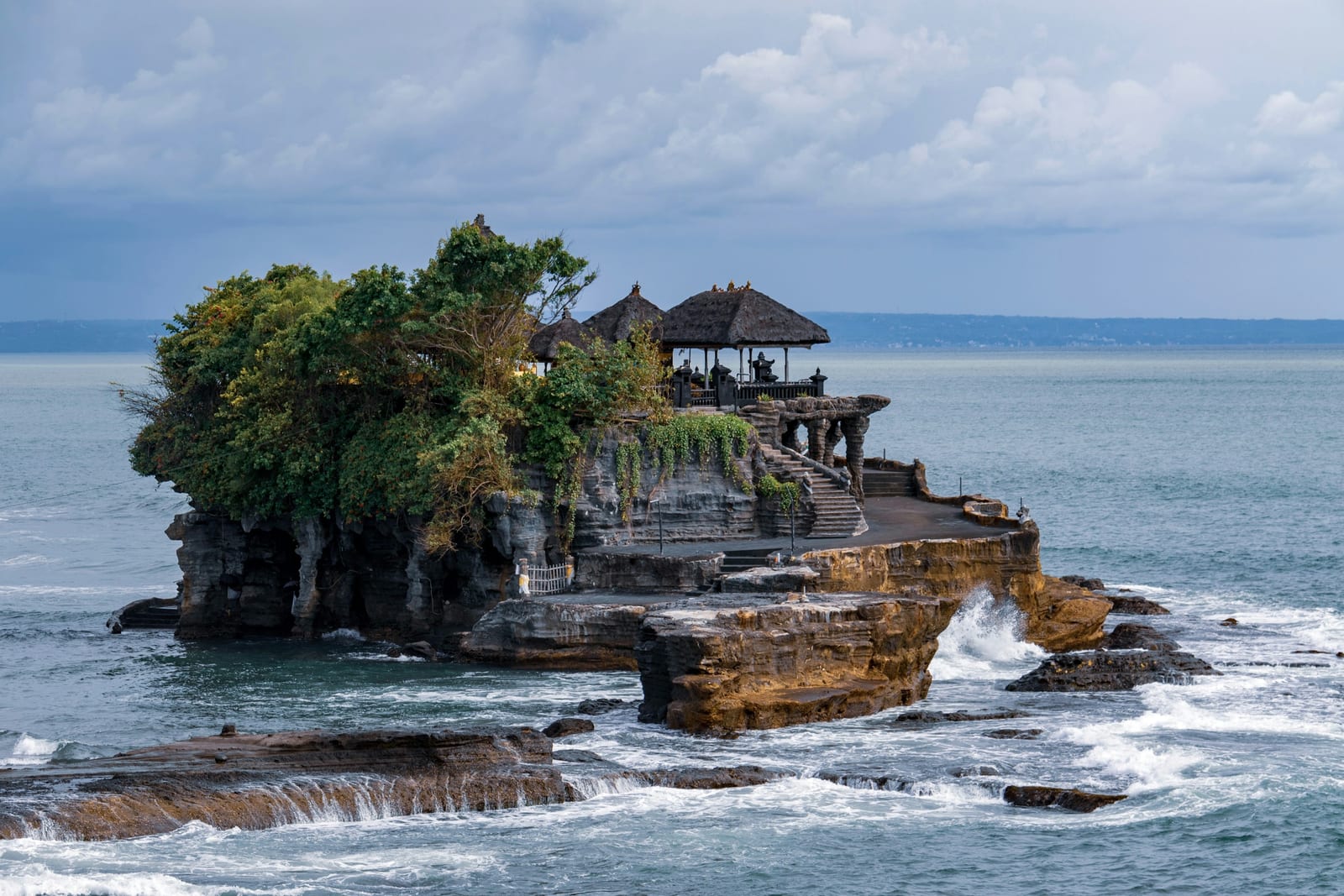 A Balinese temple stands on a rocky offshore outcrop above the sea.