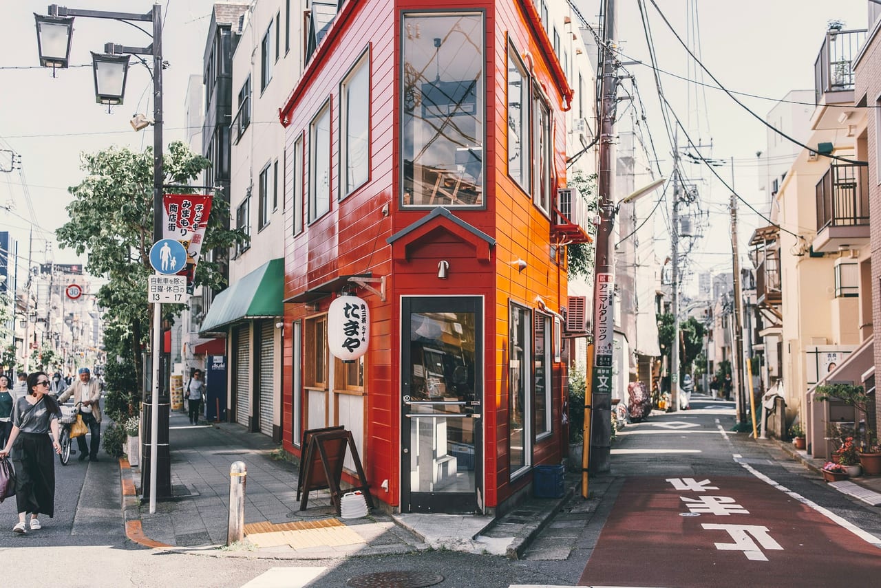 Two large painted wooden cats sit on stands lettered Yanaka Ginza at the entrance to the retro shopping street.