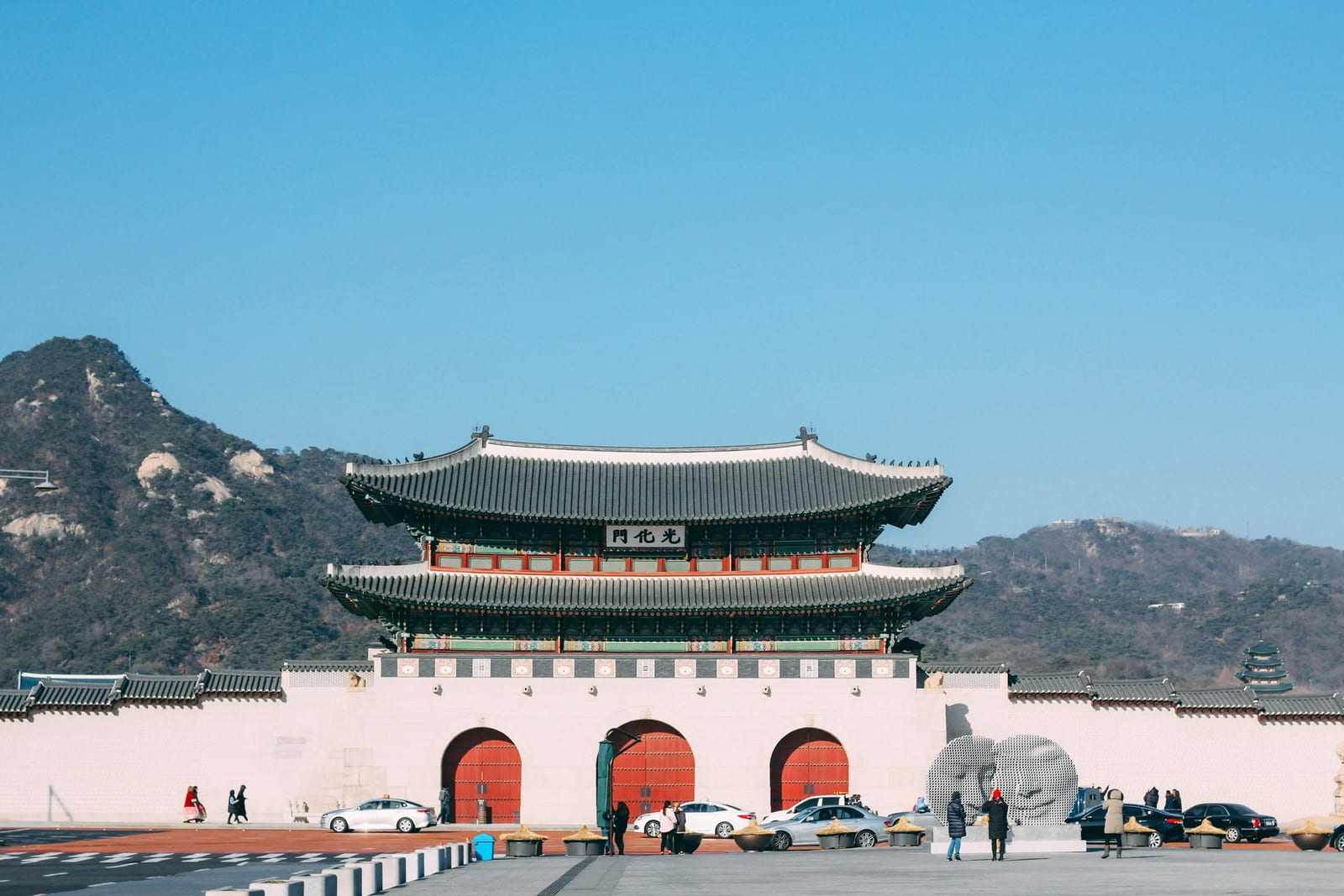 Gwanghwamun Gate stands in front of a wooded mountain in Seoul.