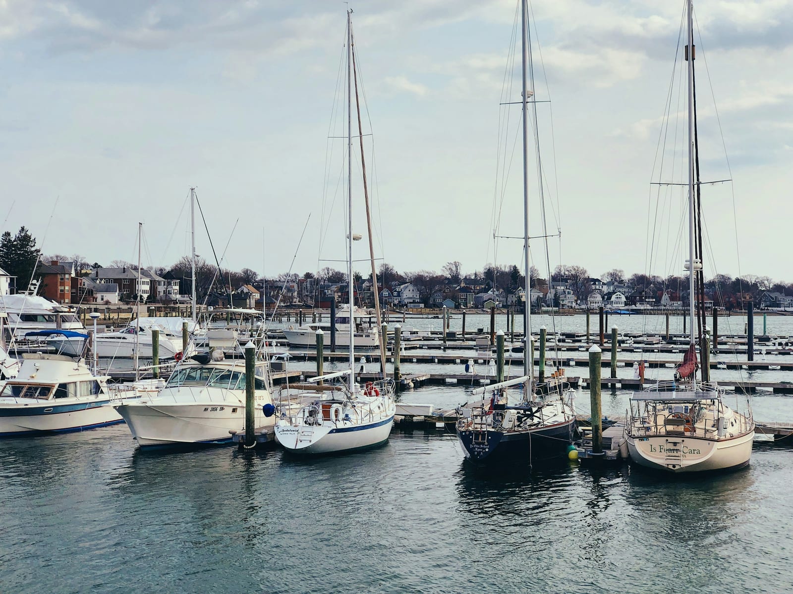 Sailboats moored in Newport Harbor with the town skyline behind.