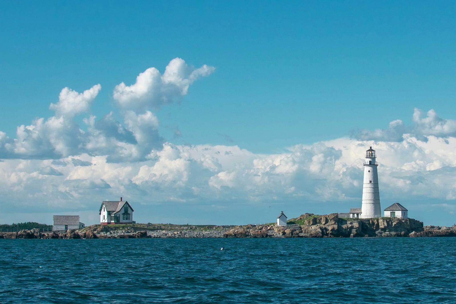 A red-and-white lighthouse on the Cape Cod coast against a blue sky.