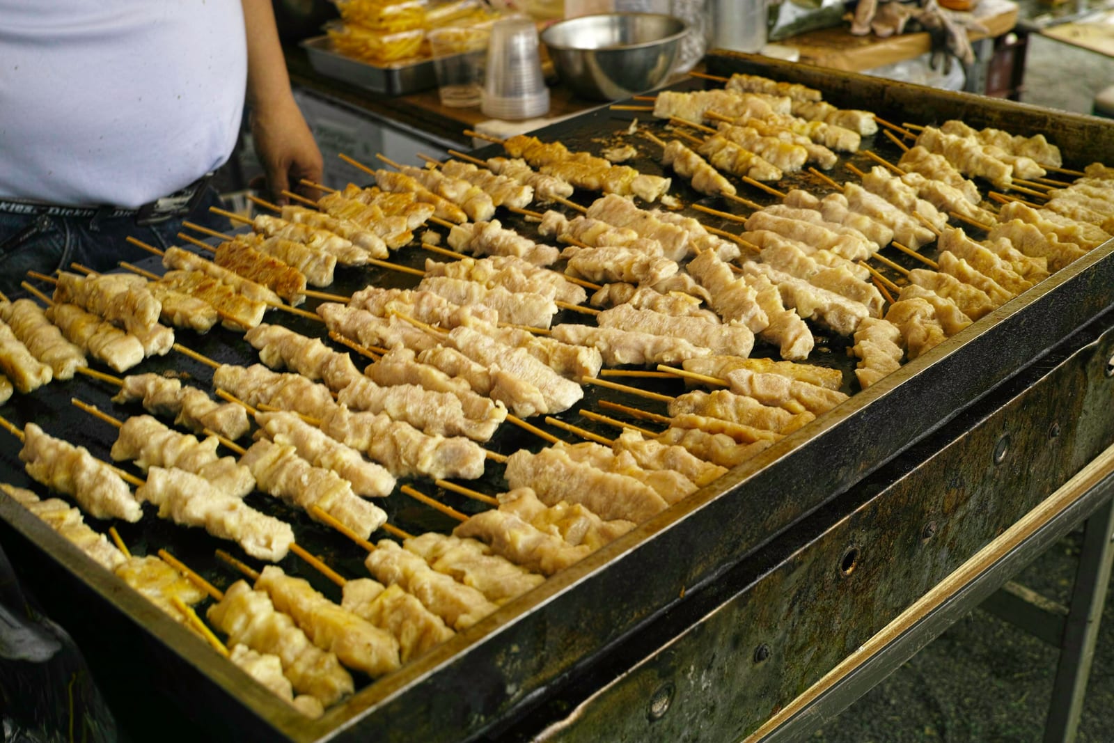 A grill stacked with yakitori chicken skewers cooking over charcoal at a Tokyo stall.