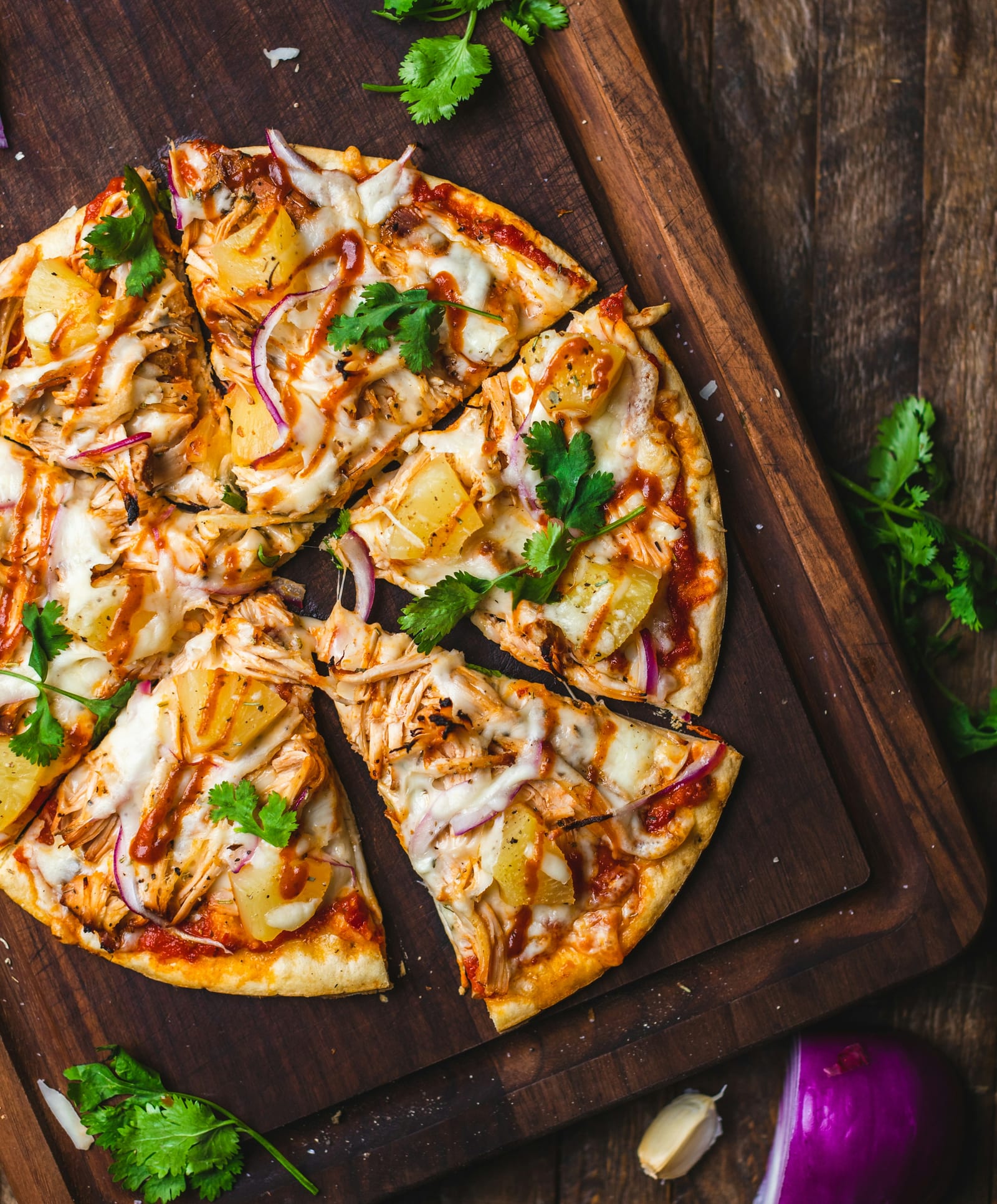 A fresh pizza with basil and tomato on a wooden board.