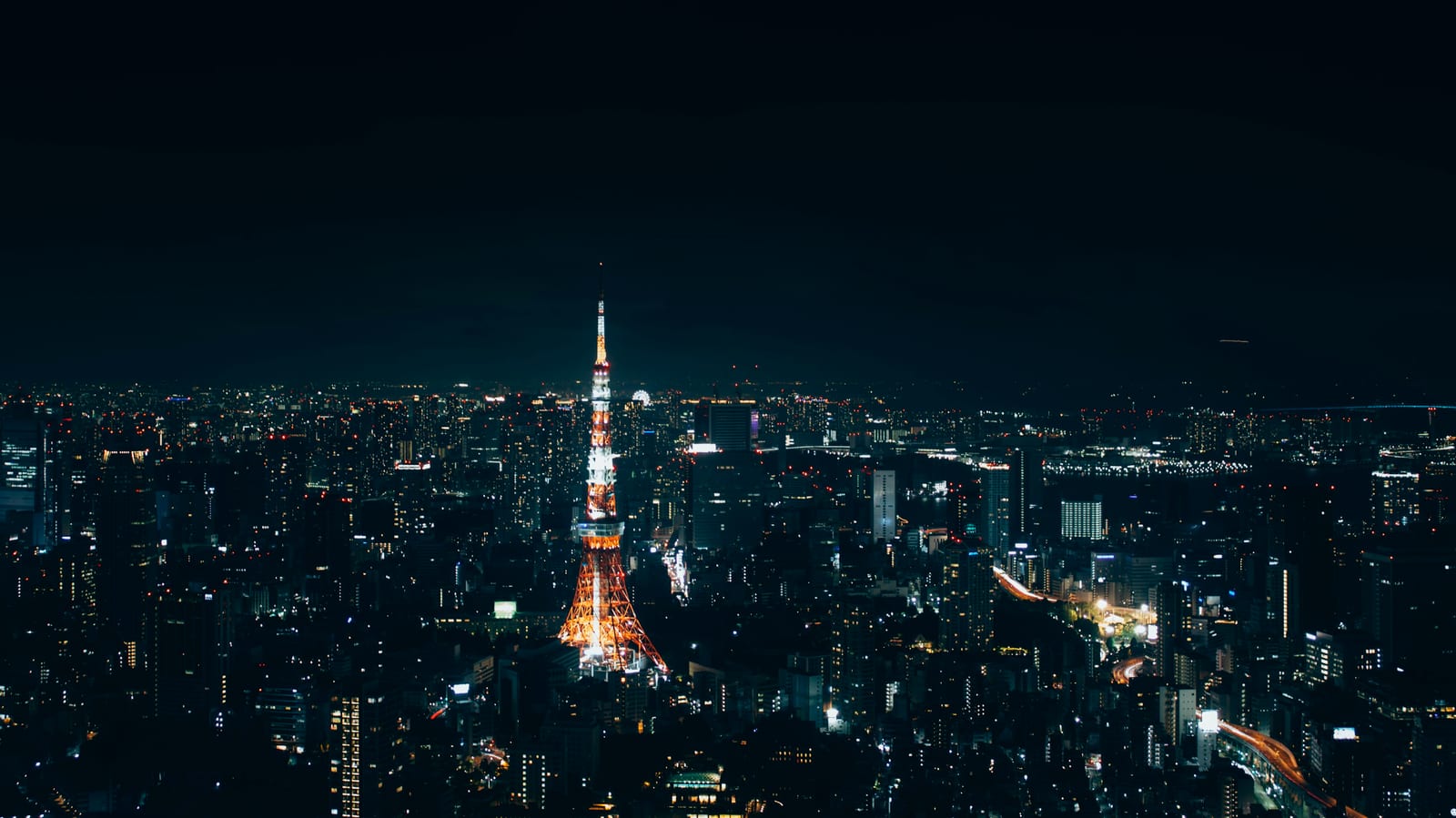 Tokyo Tower lit orange at dusk above the city skyline.