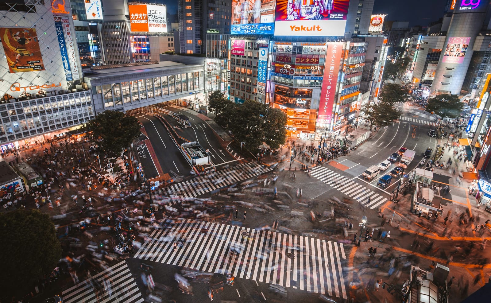 An aerial view over the dense rooftops and avenues of central Tokyo at dusk.