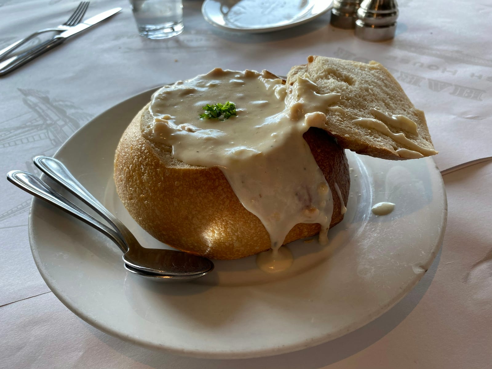 Clam chowder served in a sourdough bread bowl on a wooden table.