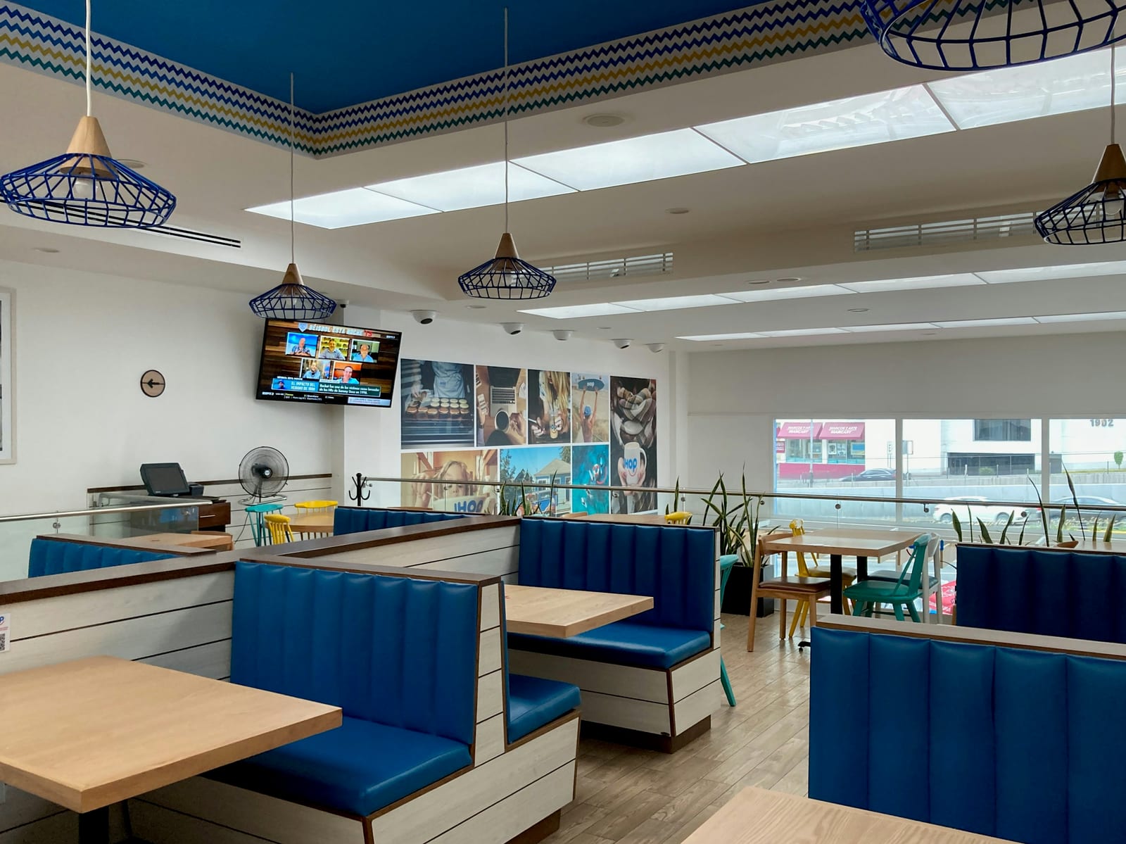 Bright casual restaurant dining room with blue booths, wooden tables, pendant lights, and seafood-themed wall displays.