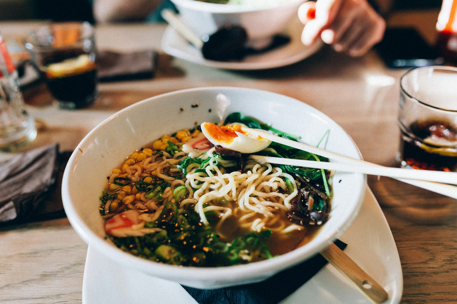 A steaming bowl of ramen with egg and greens at a Tokyo counter.