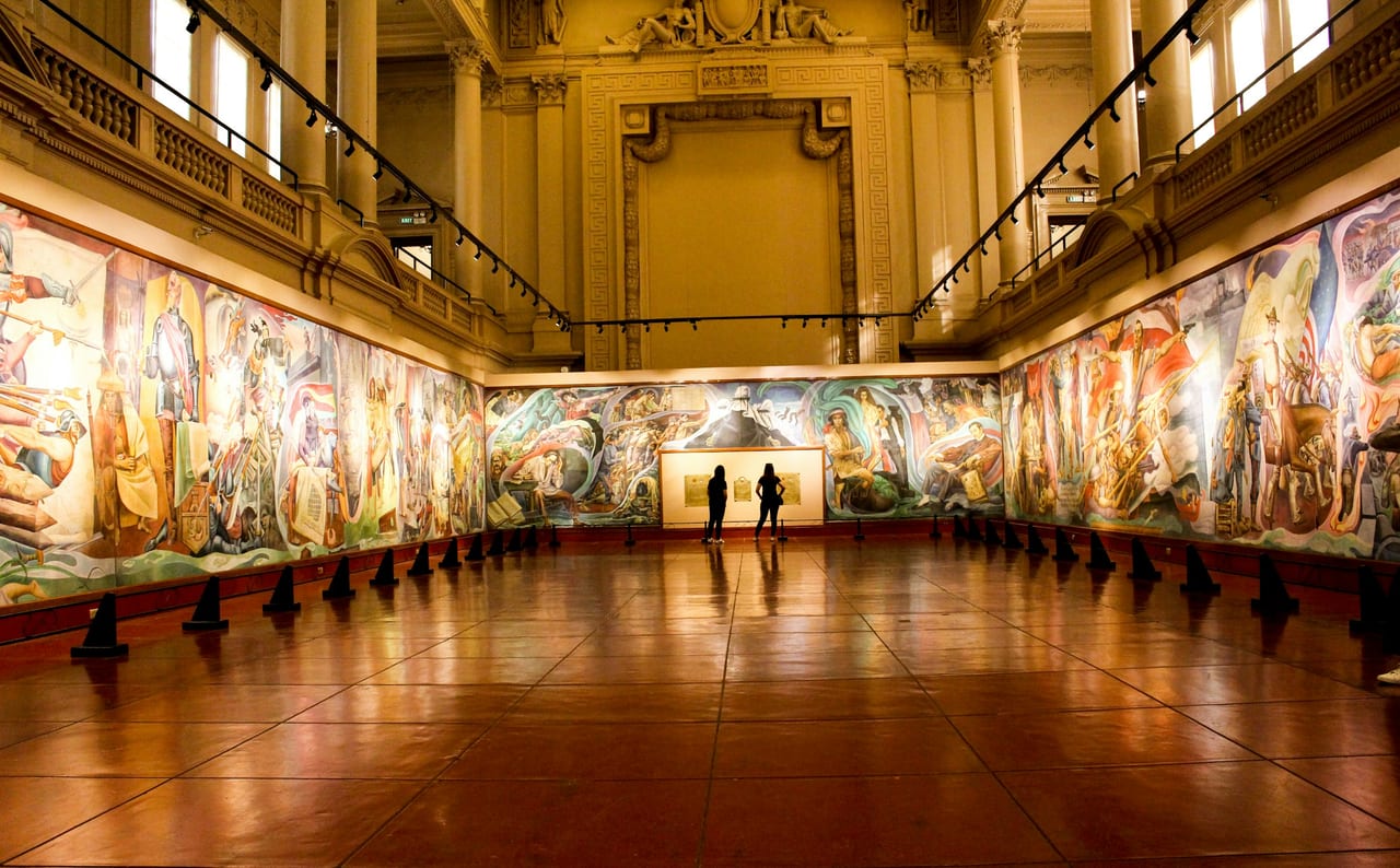 A visitor stands in a wide gallery of the Museum of Fine Arts, paintings lining the walls under soft light.