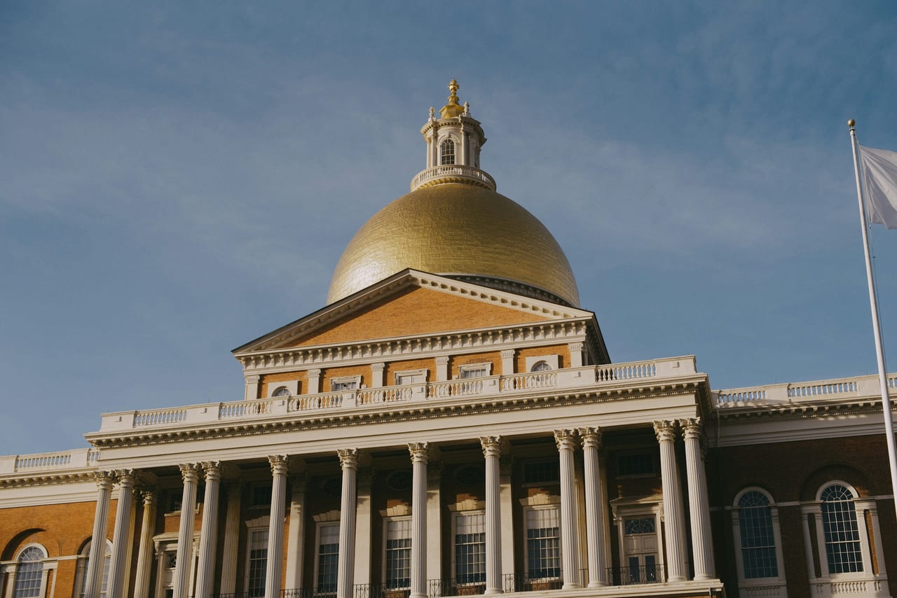 Boston's brick rowhouses and the gold dome of the Massachusetts State House rise above the autumn trees of Beacon Hill.