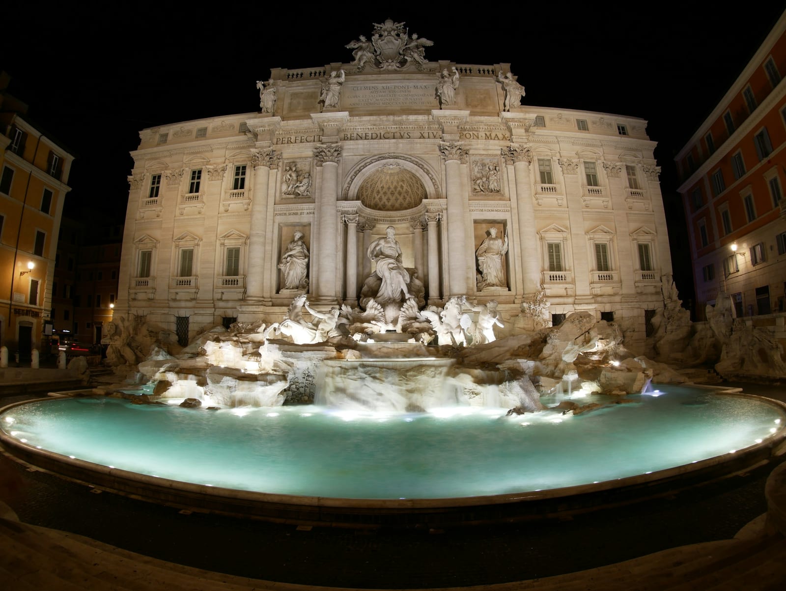 The turquoise basin of the Trevi Fountain with crowds gathered around it.
