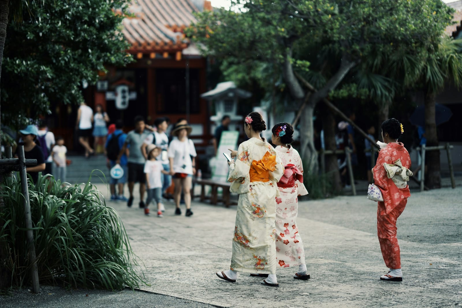 Women in colorful traditional robes walk through a temple courtyard during a cultural gathering.