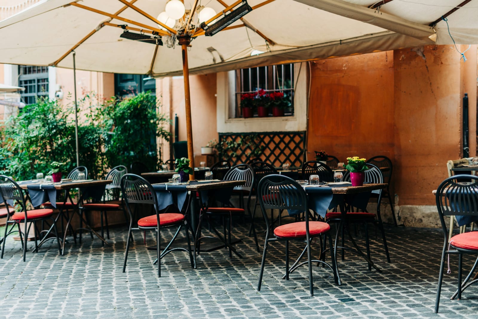 Diners at outdoor tables along a Trastevere lane in the evening.