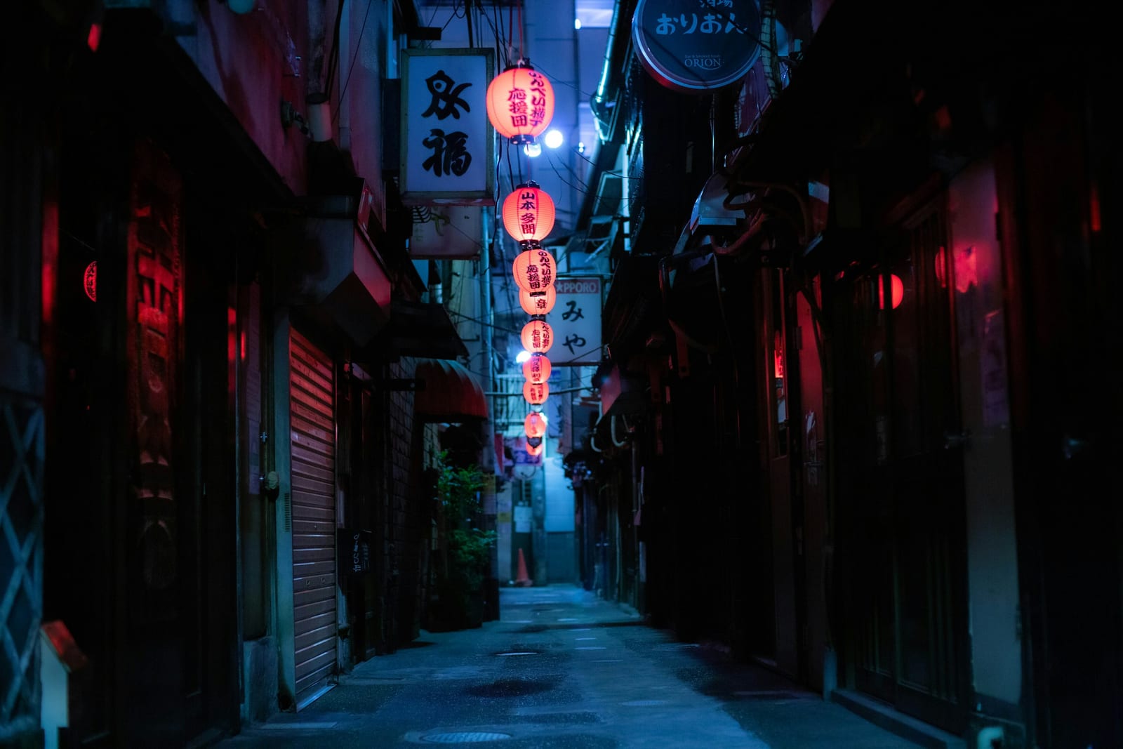 A lantern-lit alley of tiny bars in Golden Gai at night.