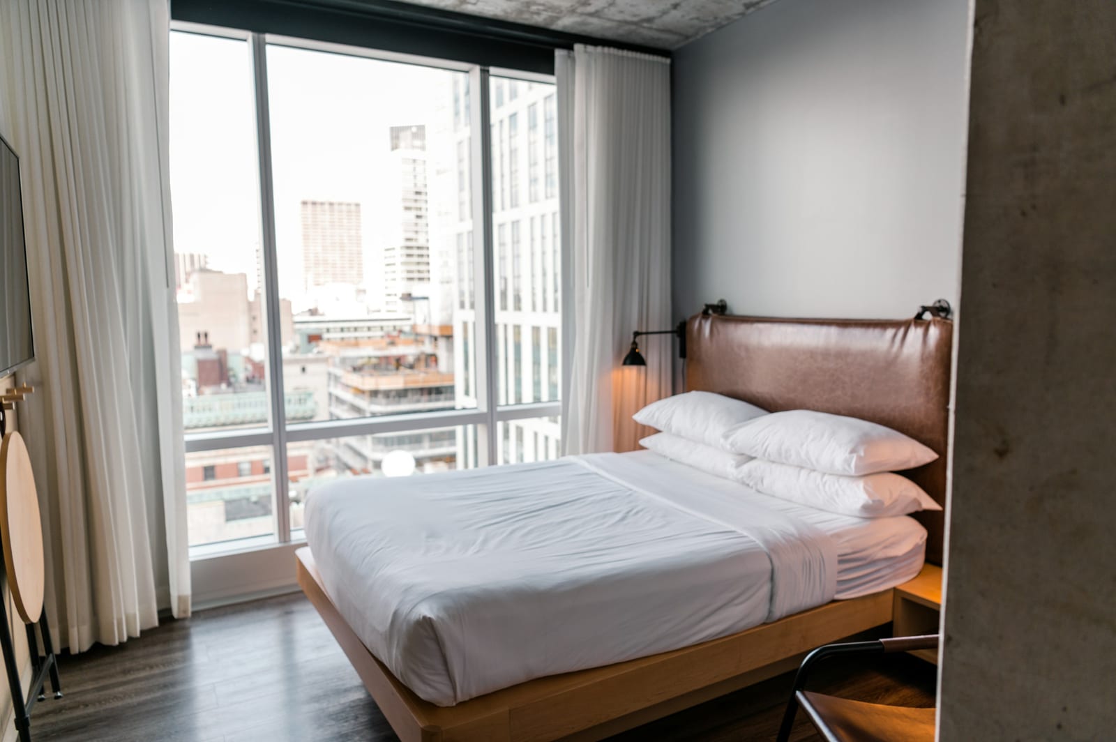A modern hotel room with a view of a city skyline through large windows.