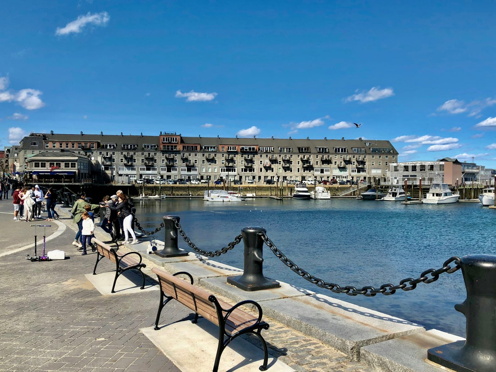 A New England harbor with fishing boats and a waterfront boardwalk.