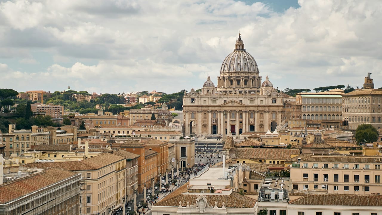 St Peter's Basilica and its great dome rise over the obelisk in St Peter's Square under a clear sky.