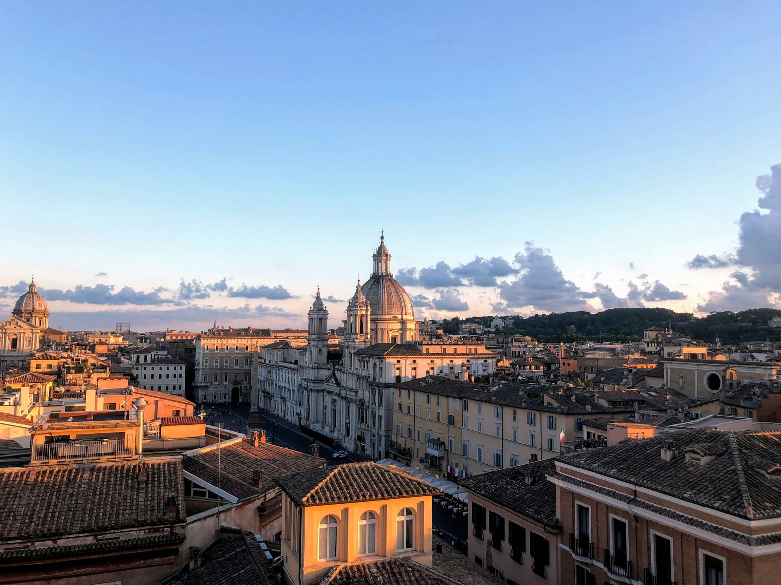 A rooftop terrace over Roman buildings in the evening light.