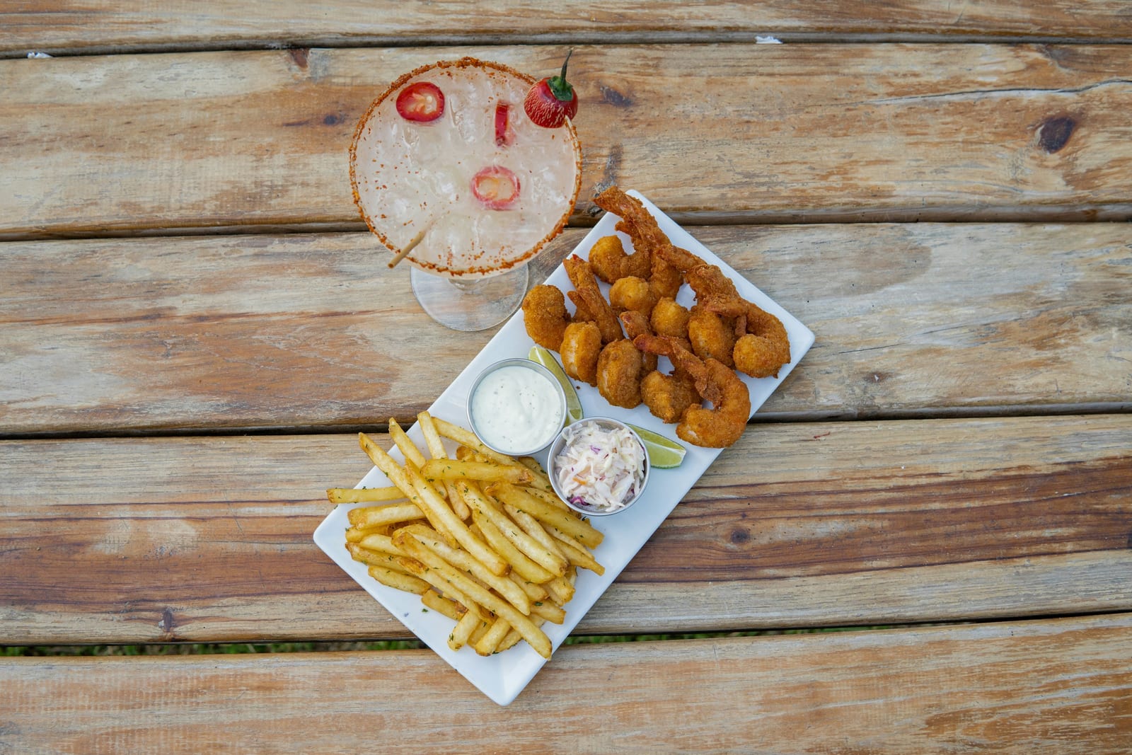 A plate of golden fried clams with tartar sauce and a lemon wedge.