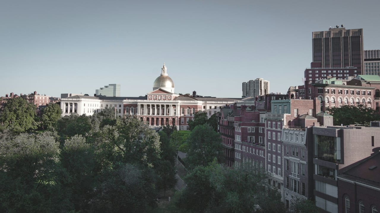 The Massachusetts State House gold dome rises above the red-brick buildings of Beacon Hill on a clear day.