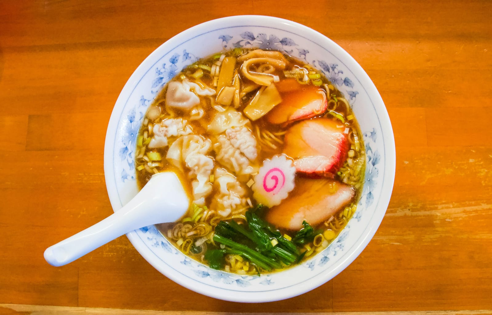 A bowl of broth-rich ramen with a spoon resting against the rim.