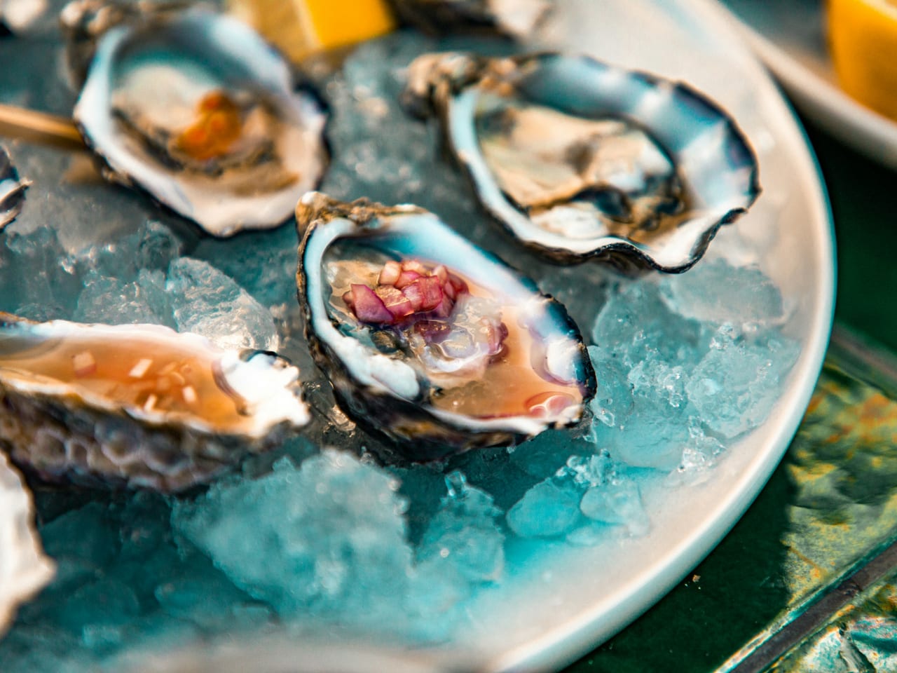 A platter of fresh oysters on ice with lemon wedges at a seafood restaurant.