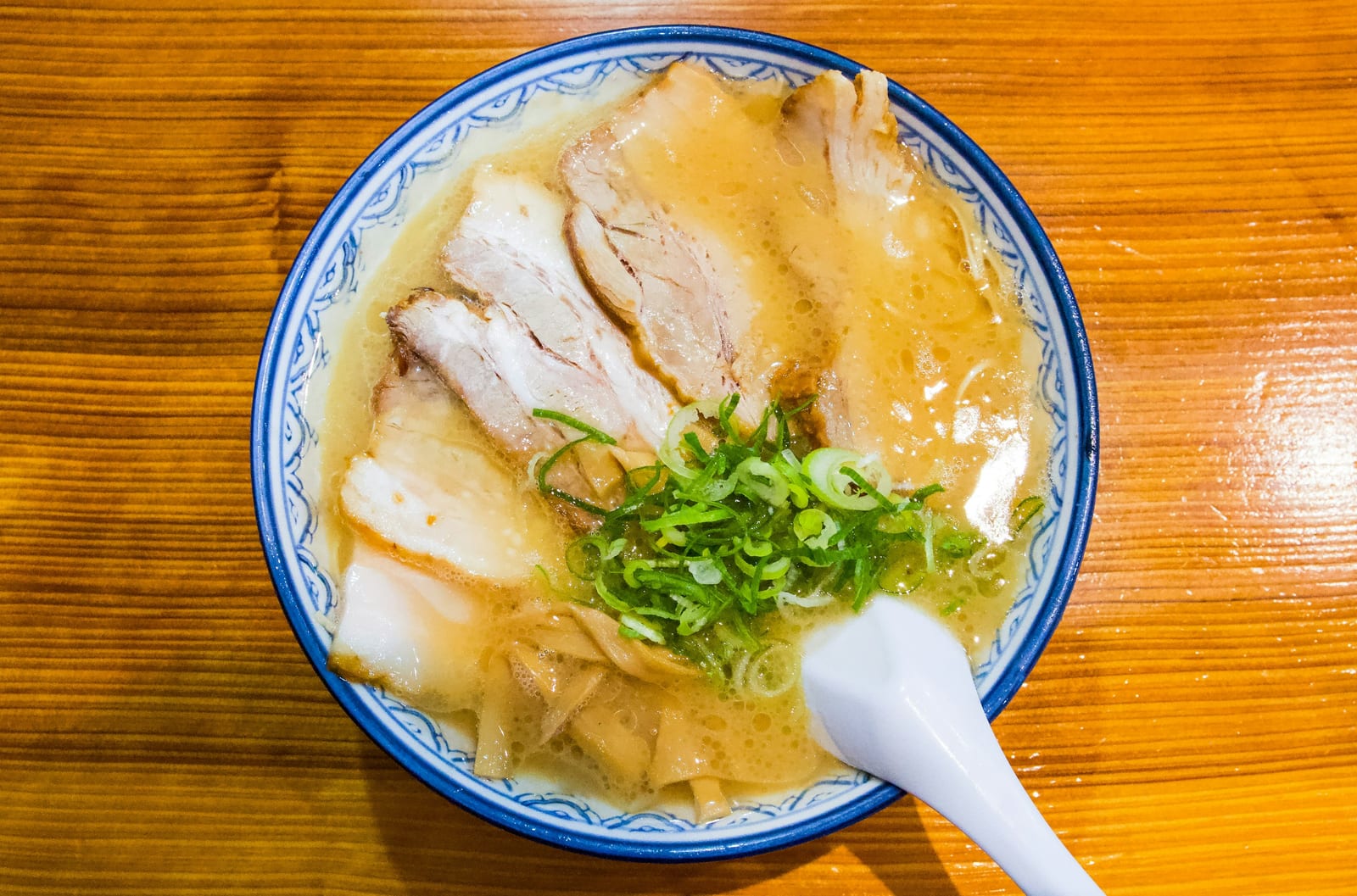 A bowl of tonkotsu ramen topped with sliced pork and scallion.